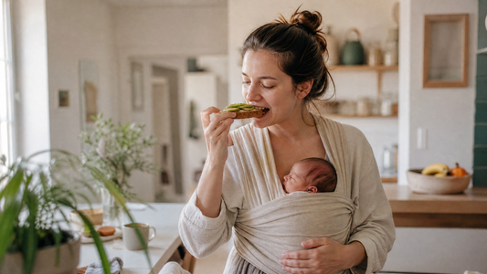Maman qui porte son bébé en écharpe et mange d'une main parce qu'il ne veut pas être posé
